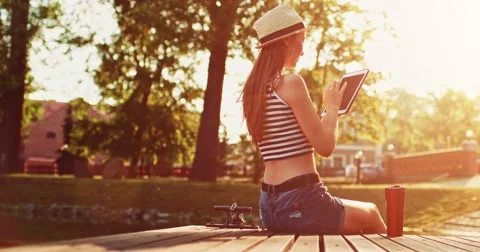 Woman using digital tablet sitting on a wooden jetty by the lake. Slow Motion. Stock Footage 66856155
