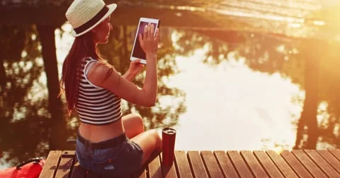 Woman using digital tablet sitting on a wooden jetty by the lake. Slow Motion. 스톡 동영상 66856255
