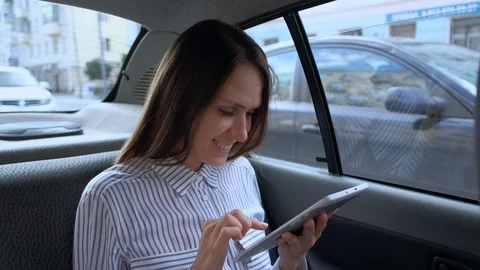 Woman using a digital tablet sitting in backseat car taxi. Stock-Footage 114810639