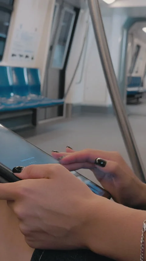 Woman using digital tablet on subway, engaged in navigation, with empty seats Stock Footage 317076647