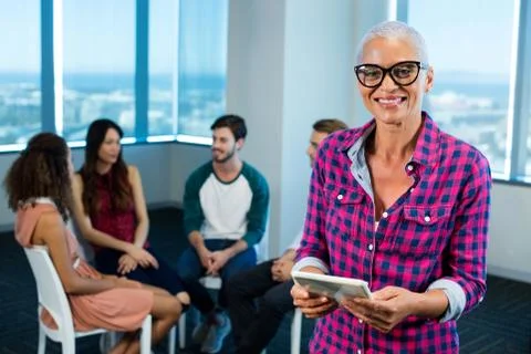 Woman using digital tablet while creative business team in background Foto stock