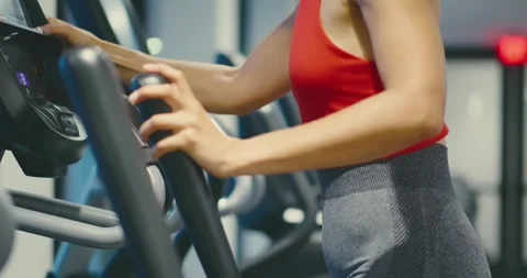 Woman Using Elliptical Machine in Modern Gym Stock Footage 323718463