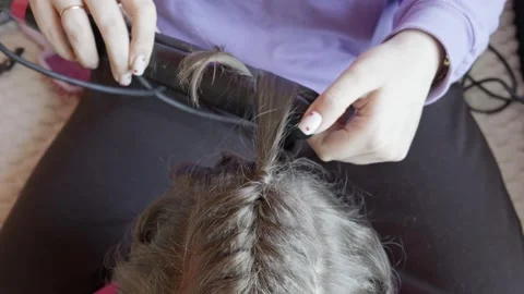 Woman Using Flat Iron To Curl Young Girls Braided Hair At Home Stock Footage 330418763