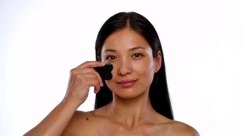Woman Using Gua Sha Tool for Facial Massage Routine Stock Footage 314164827