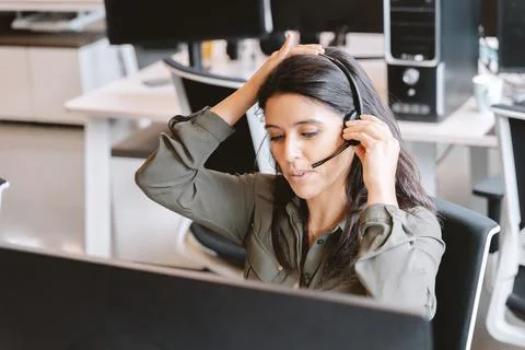 Woman using a headset while working in the office. Fotos Stock
