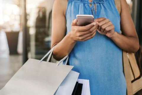 Woman using her cellphone while out clothes shopping Stock Photos