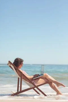 Woman using her laptop while sitting on a chair Fotos Stock