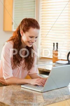 Woman using her notebook in the kitchen Stock Photos