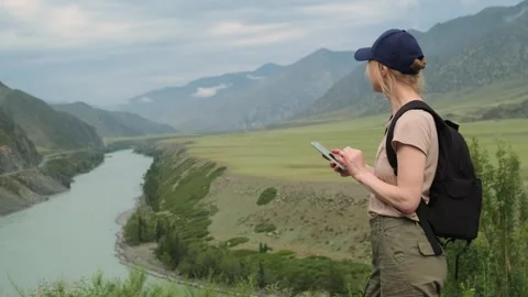 Woman using her smartphone while hiking in the mountains. Stock Footage 297752073