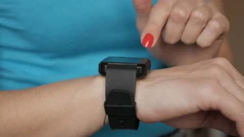 Woman using her smartwatch touchscreen wearable technology device. Girl makin Video stock 127987103