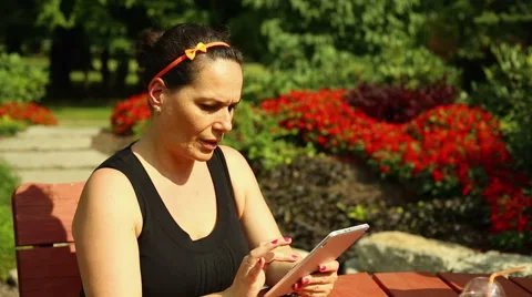 Woman is using her tablet, sitting at the park Stock Footage 65823016
