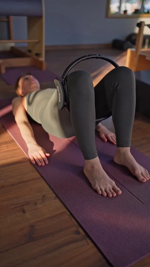 A woman is using a hip Magic Circle at Glute bridge Pilates workout in studio Video stock 279860306