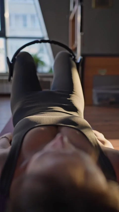A woman is using a hip Magic Circle at Glute bridge Pilates workout in studio Stock Footage 280277308