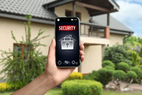Woman using home security system application on smartphone outdoors, closeup Stock Photos