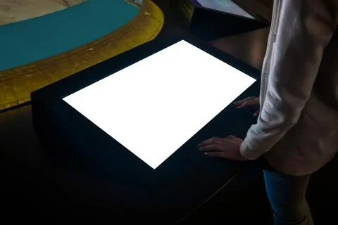 Woman using interactive empty white touchscreen display kiosk at exhibition Stock Photos