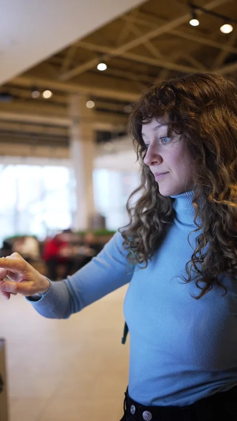 Woman using interactive touchscreen kiosk in public space Stock Footage 303604204