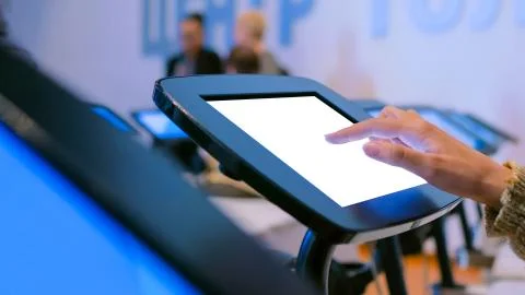 Woman using interactive touchscreen kiosk with white empty screen Stock Photos
