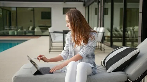 Woman using iPad pro sitting next to a pool 스톡 동영상 101488047