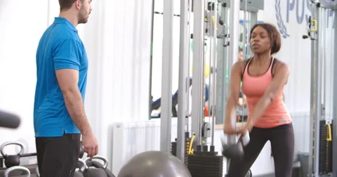 Woman using a kettlebell weight with a trainer in a gym Stock Footage 56211883