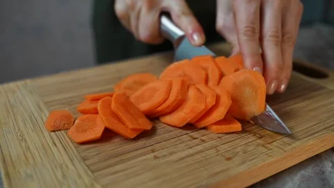 Woman using a knife to slice a fresh carrot Video stock 303573892