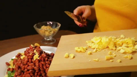 A woman is using a knife to sprinkle grated cheese into a plate of salad Stock Footage 103223073