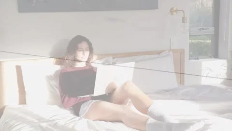Woman using laptop in bed for tech work, sunlight moving causing head turns, Stock Footage 332956463