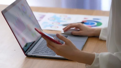 Woman using a laptop computer and a smart phone in the office. Stock Footage 127039540
