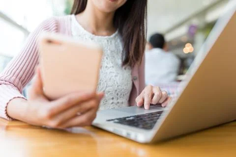 Woman using laptop computer and cellphone Stock Photos