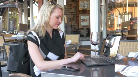 Woman using laptop computer at cafe with glass of wine - 4K Stock Footage 48935422