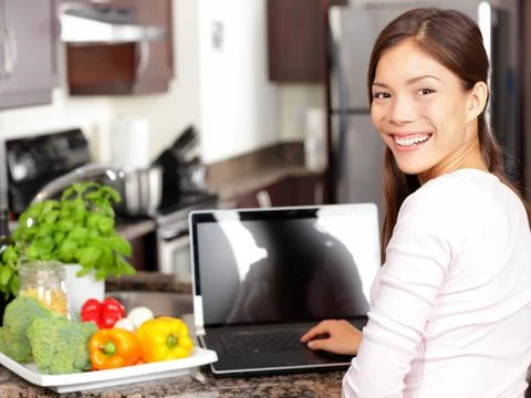 Woman using laptop computer in kitchen Stock Photos