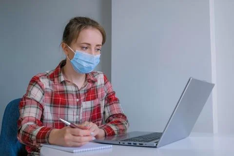 Woman using laptop computer, making notes in grey room at home 写真素材