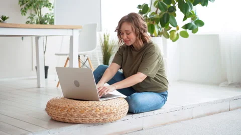 Woman using laptop computer while sitting floor at home interior Stock Footage 152182478