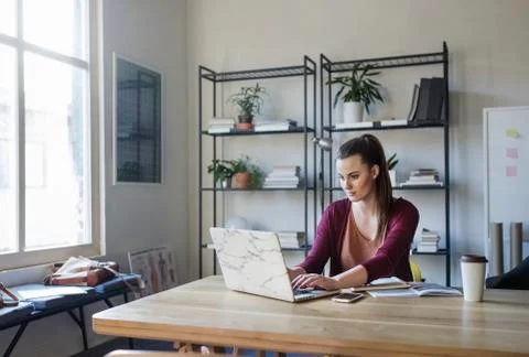 Woman using laptop computer while studying a table in classroom Stock Photos