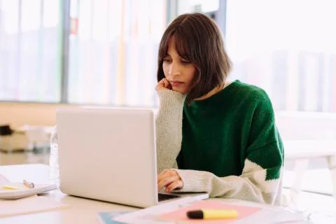 Woman using laptop computer while sitting at table in library Stockfoto's