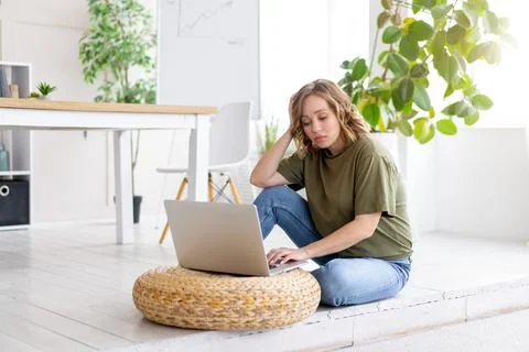 Woman using laptop computer while sitting floor at home interior. Freelance f Stock-Fotos
