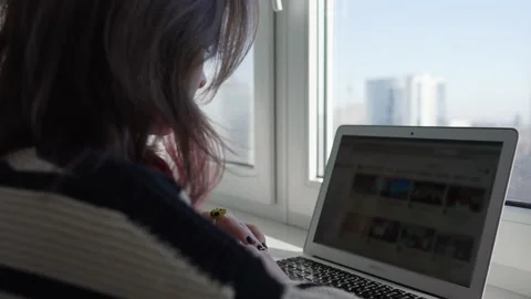 Woman using laptop computer by window overlooking city Video stock 171922157