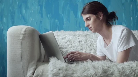 Woman using laptop at home while lying on the couch. Stock Footage 103508630