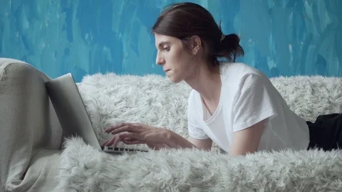 Woman using laptop at home while lying on the couch. Stock Footage 103508731