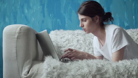 Woman using laptop at home while lying on the couch. Stock Footage 103508817