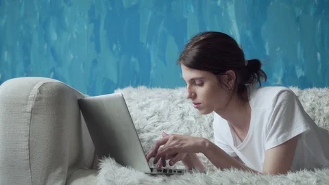 Woman using laptop at home while lying on the couch. Stock Footage 103508918
