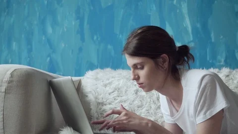 Woman using laptop at home while lying on the couch. Stock Footage 103509056