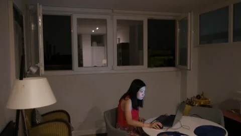 A woman is using a laptop indoors while a thunderstorm is taking place Stock Footage 267677515