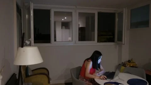 A woman is using a laptop indoors while a thunderstorm is taking place Stock Footage 267677525