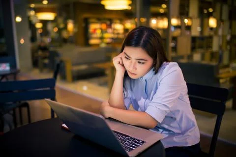 Woman  using laptop in night time at cafe  she feel worried Stock Photos