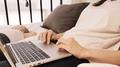 Woman Using Laptop While Baby Sleeps Nearby Stock Footage