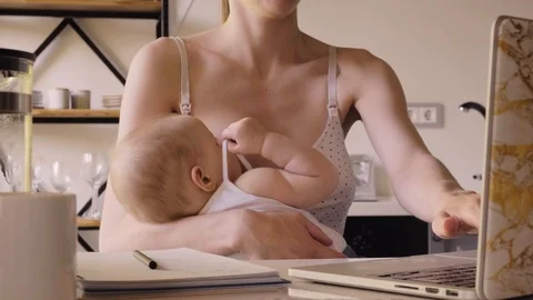 Woman Using Laptop While Feeding Baby Stock Footage 114769918