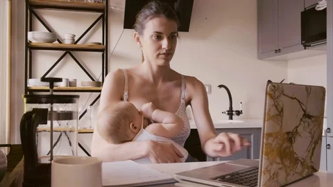 Woman Using Laptop While Feeding Baby Stock Footage 130012654