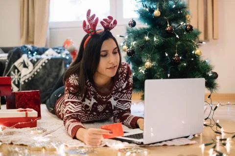 Woman using laptop while lying on floor with tree and presents Stock Photos