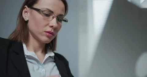 Woman is using laptop while sitting at her desk. Young european businesswoman is Stock Footage 194482698