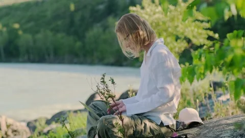 Woman using a laptop while sitting on the stone near mountain river. Stock Footage 313422155